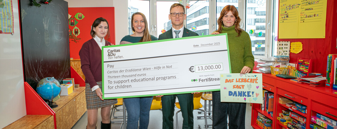 Vier Personen halten einen Spendenscheck über 13.000 € für das Caritas-Lerncafé Wien und ein Dankesplakat hoch.