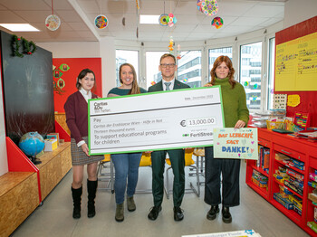 Vier Personen halten einen Spendenscheck über 13.000 € für das Caritas-Lerncafé Wien und ein Dankesplakat hoch.