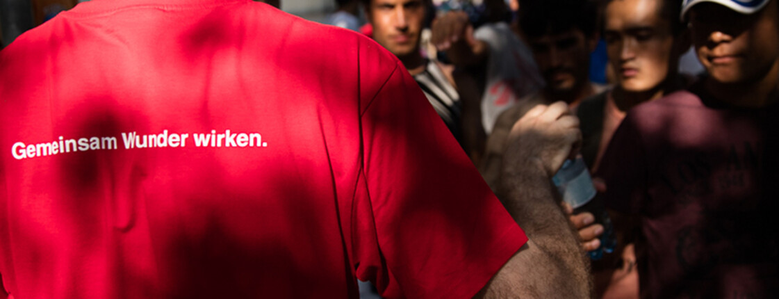 Caritas Helfer übergibt Hilfsgüter an Flüchtlinge