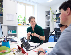 Sozialarbeiterin spricht mit einem Jugendlichen, der im Büro des JUCA telefoniert