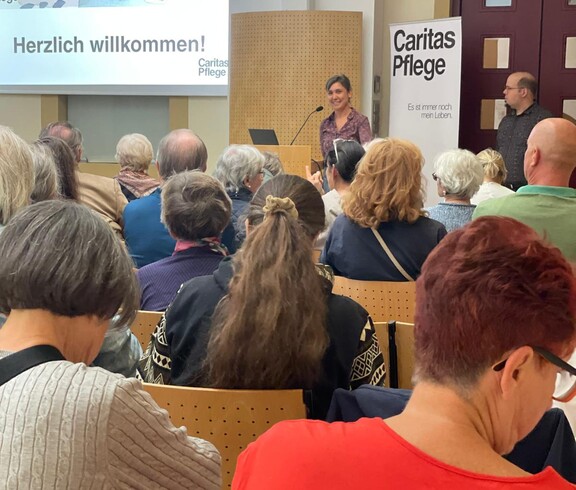 Caroline Leitner spricht auf einer Bühne, Menschen sitzen davor in Reihen.