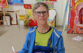 Künstler mit Brille malt mit Marker im Atelier der Caritas-Kunstgruppe im Weinviertel.