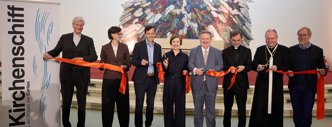 Eine Personengruppe durchschneidet ein rotes Band.