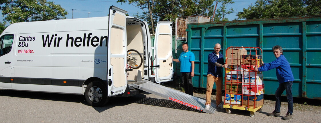 Gemeinsam werden von drei Freiwilligen Sachspenden in einen LKW geladen.