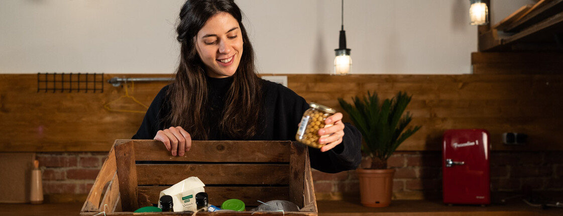 Junge Frau befüllt Holzkiste mit haltbaren Lebensmittel
