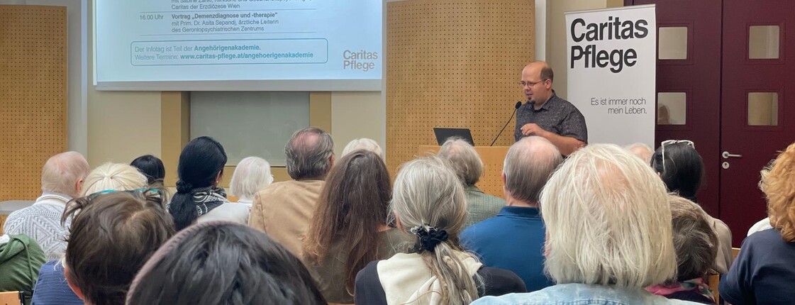 Menschen sitzen auf Stühlen und lauschen einem Vortrag Caritas Infotag für Angehörige