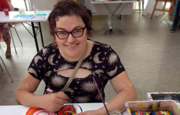 Künstlerin zeichnet farbiges Bild im Atelier der Caritas-Kunstgruppe im Weinviertel.