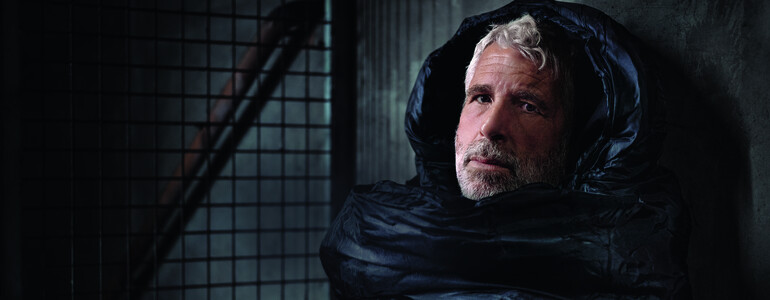 Der Fernsehmoderator Dirk Stermann als Obdachloser im Schlafsack abgebildet