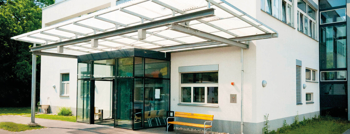 Tagesstätte Rannersdorf Außenansicht der Tagesstätte in Rannersdorf. Weißes Flachdachgebäude mit gläsernem Vordach