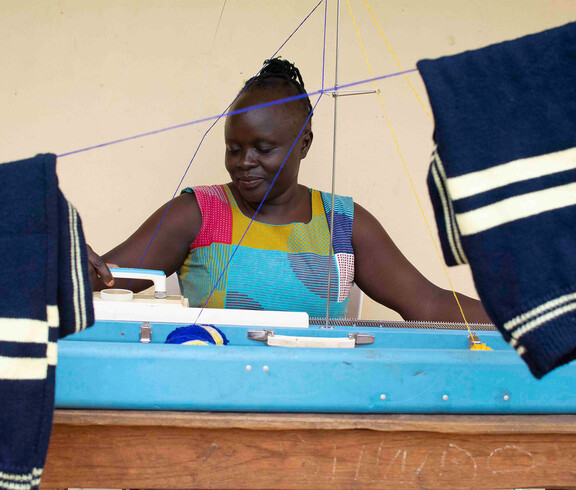 Schneiderin fertigt blau-weiß gestreifte Stoffe an Strickmaschine im Südsudan