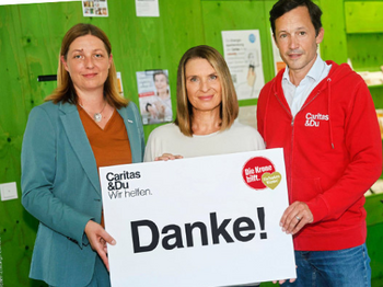 Nora Tödtling-Musenbichler, Barbara Stöckl und Klaus Schwertner (von links nach rechts) halten gemeinsam ein großes Dankesschild der Hilfsorganisation Caritas in die Kamera.