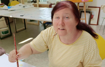 Künstlerin zeichnet mit einem Pinsel im Atelier der Caritas-Kunstgruppe im Weinviertel.