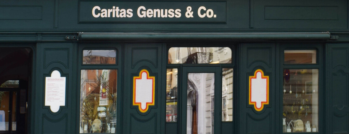 Grüne Außenfassade aus Holz, des Shops Caritas Genuss & Co. 