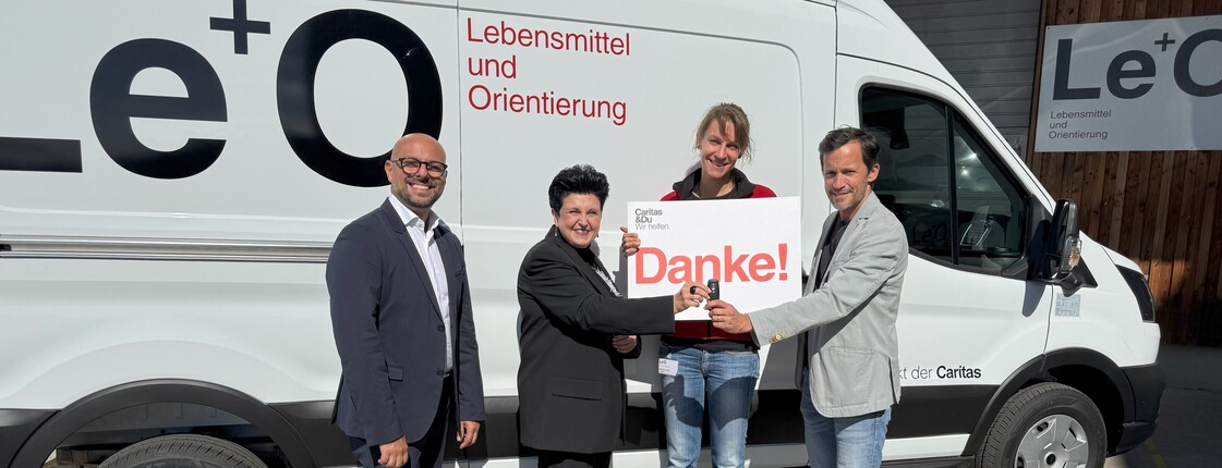 Vertreter*innen von Hoerbiger und von Caritas stehen vor dem Le+O Transporter