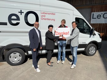 Vertreter*innen von Hoerbiger und von Caritas stehen vor dem Le+O Transporter