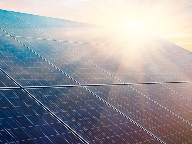 Photovoltaikmodule reflektieren Sonnenlicht unter hellem Himmel und stehen für erneuerbare Energiegewinnung.