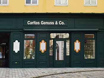Grüne Außenfassade aus Holz, des Shops Caritas Genuss & Co. 