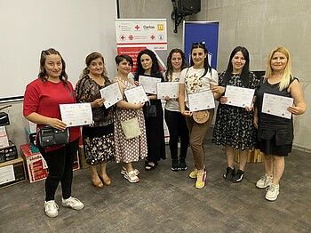 Acht Frauen halten Zertifikate ihres erfolgreichen Ausbildungsabschlusses in die Kamera.