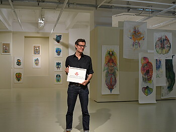 Der Leiter des Atelier 10, Florian Reese, vor Werken von Ivana Kralj.