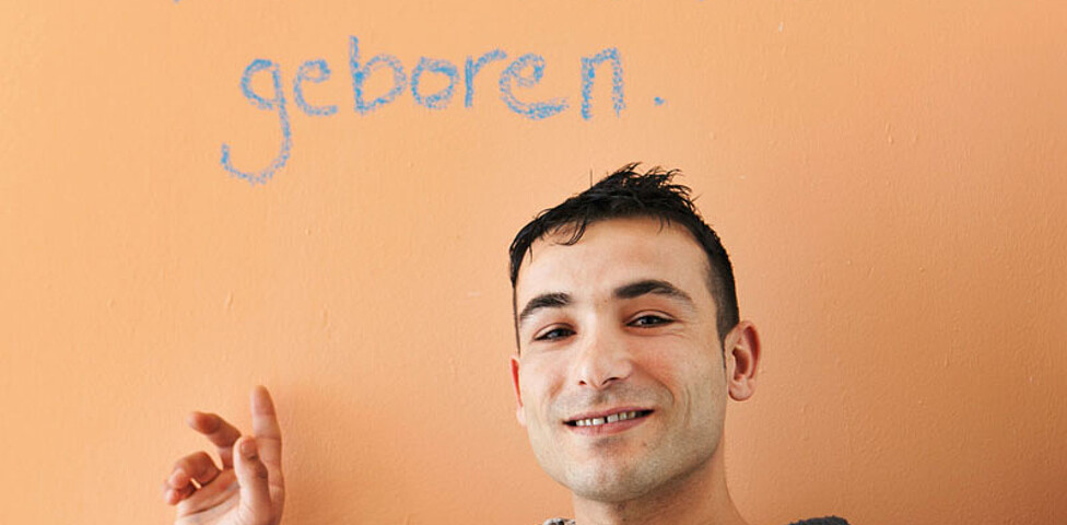 Junger Flüchtling vor der Aufschrift "Ich bin hier neu geboren"