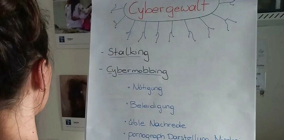 Mädchen vor Flipchart mit Begriffen zum Thema Cybergewalt, Stalking und Mobbing