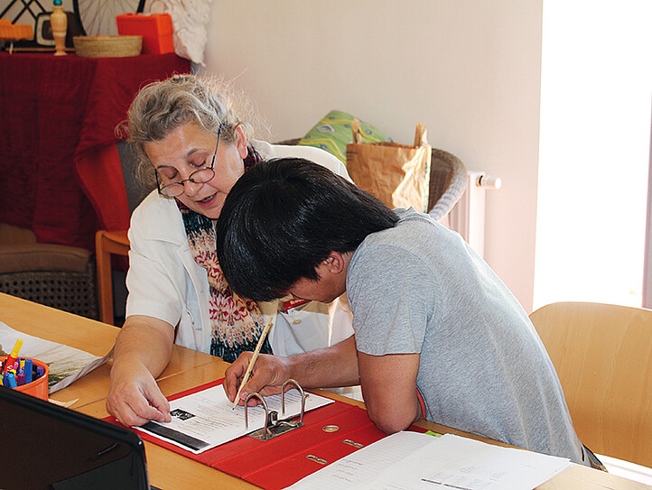 junger Flüchtling lernt mit freiwilliger Mitarbeiterin
