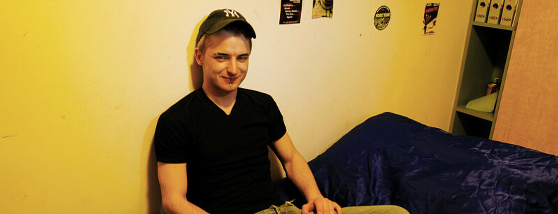 Ein junger Mann sitzt auf einem Bett