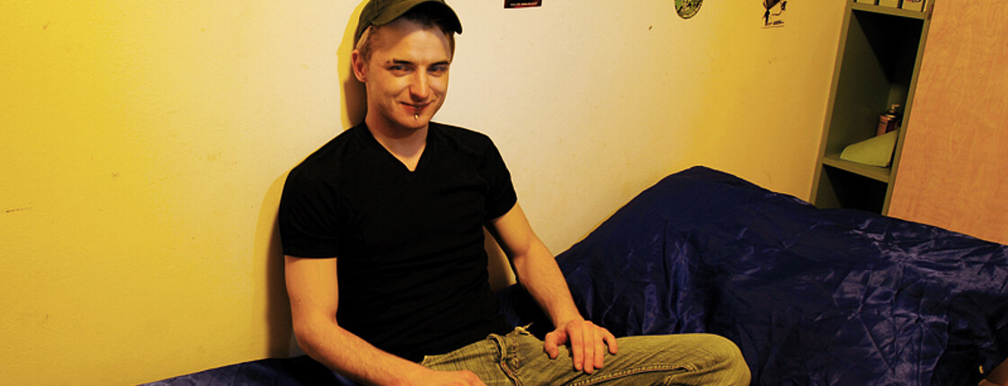 Ein junger Mann sitzt auf einem Bett